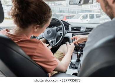 back view of father pointing with finger while showing teenage son how to start car - Powered by Shutterstock