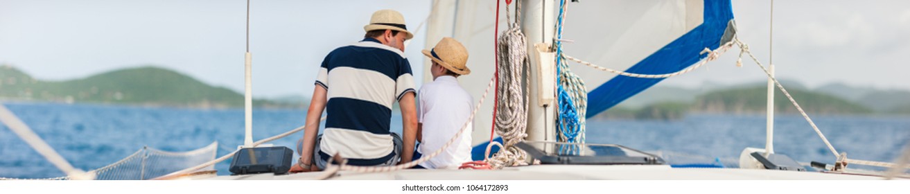 Back View Of Father And Son Family Sailing On A Luxury Yacht Or Catamaran Boat