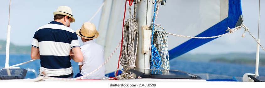 Back View Of Father And Son Family Sailing On A Luxury Yacht Or Catamaran Boat