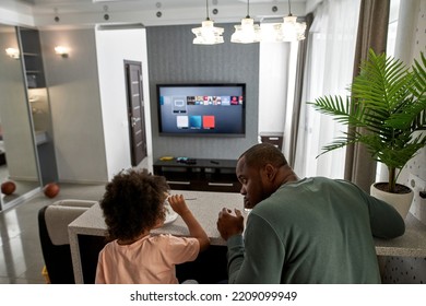 Back View Of Father And Son Look At Each Other During Have Lunch Or Dinner With Cola And Pizza At Home Kitchen. Unhealthy Eat. Young Black Family Lifestyle And Relationship. Fatherhood And Parenting