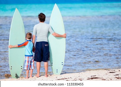 Back view of father and son with surfboards at beach - Powered by Shutterstock