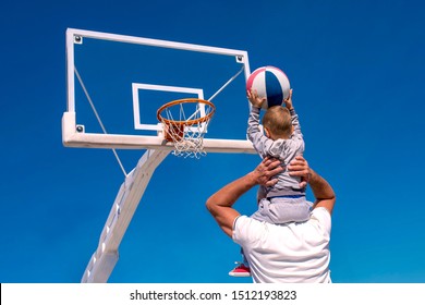 Back View Of Father Teaching Son To Play Basketball 