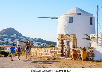 Back View Of Father And Two Kids On Milos Island Vacation In Greece Walking By Traditional White Windmill