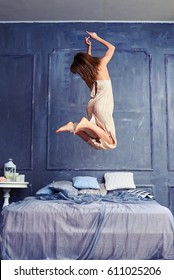 Back view of a female in the air. Woman jumping with knees bent. Wearing long nightgown having fun early in the morning 