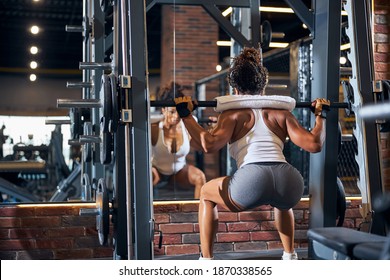 Back View Of A Female Athlete Doing The Barbell Back Squat Using The Power Rack