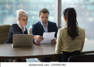 Back view of female candidate apply for position, interview in modern office, recruiters consider applicant candidature, reading resume, HR managers look through employee cv. Hiring concept - Powered by Shutterstock