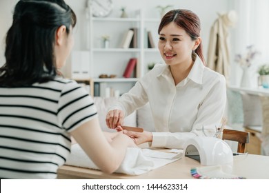 back view of female customer at home receiving manicure by smiling beautician with nail file. friendly manicurist file nails to lady client. elegant nail specialist working in guest house. - Powered by Shutterstock