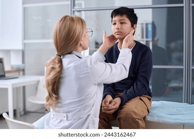 Back view of female doctor examining neck and throat of young boy during health check up in pediatric clinic - Powered by Shutterstock