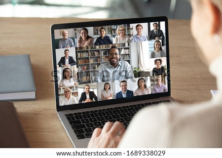 Photo of Back view of female employee speak talk on video call with diverse multiracial colleagues on online event briefing, woman worker have Webcam group conference with coworkers on modern laptop at home