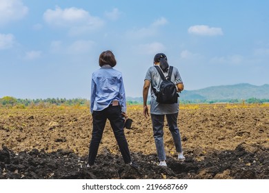 Back View Of Female Farmer Friend Holding Mobile Phone And Discuss Soil Quality For Farming In Field. Agriculturist Women Consult Each Other About Cultivation In Meadow. Farm And Agricultural Business