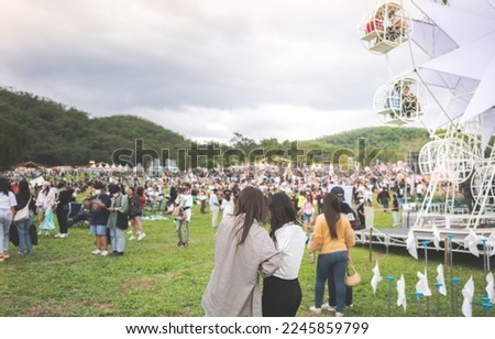 Back view of female friends watching concert in the park at open air, in front of stage.