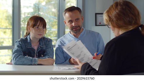 Back view of female headmaster interview father and preteen girl in school office. Smiling mature man with teenage daughter meeting woman principal