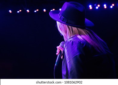 Back view of a female singer on the stage. Dark background, concert spotlights. - Powered by Shutterstock