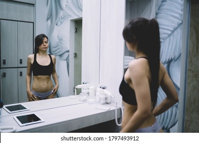 Back View Of Female With Slim Figure In Lingerie Looking At Mirror Satisfied With Slimming Results, Beautiful Caucasian Young Woman Enjoying Training Prepare For Workout In Modern Locker Room