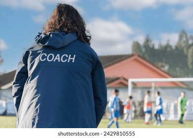 Back view of a female sport coach watching her team compete at an outdoor football field. High quality photo - Powered by Shutterstock