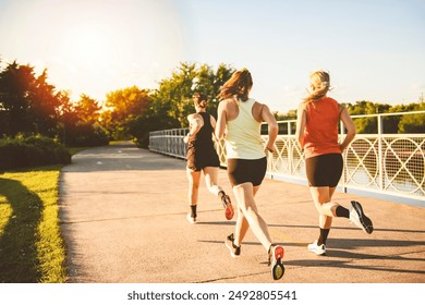 The back view of females in sportswear jogging together bright sunny park in summer - Powered by Shutterstock