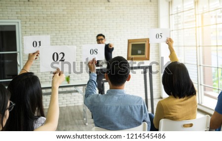 Back view of fighting bidder group showing bidding number offer. Auctioneer in front room with empty space picture frame for your montage Auction project successful, business competition trade concept