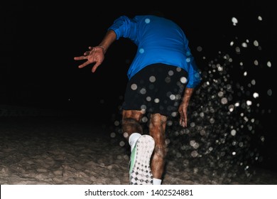 Back View Of A Fit Young African Sports Man Wearing Windbreaker Exercising Outdoors At Night Time, Running At The Beach