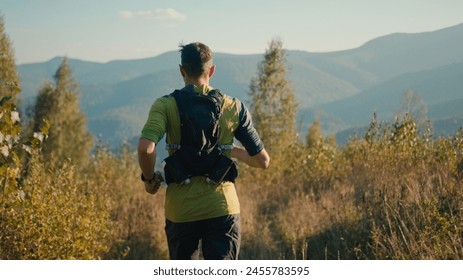 Back view focused Caucasian male man person runner guy mountaineer sportsman running jogging trail outside countryside meadow mountain hill sunshine. Sport motivation healthy lifestyle workout fitness - Powered by Shutterstock