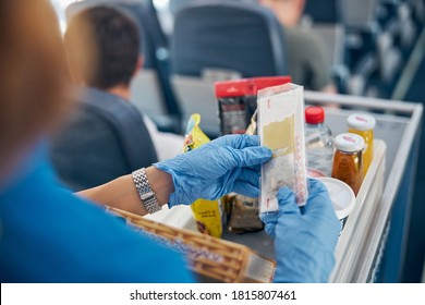 Back View Focused Image Of Table With Snack And Drinks While Female Air Hostess Serving Meal For The Passenger Of First Class