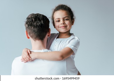 back view of foster father hugging happy adopted african american daughter isolated on white