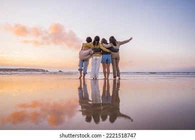 Back view of the four girls embracing and enjoying of the golden sunset at the ocean - Powered by Shutterstock