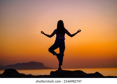 Back view of free calm bliss satisfied woman standing on top rock with yoga position against of idyllic sunset sky by the sea in a happy beautiful inspired moment of her life - Shutterstock ID 2146982747