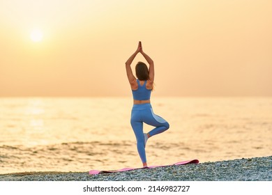 Back View Of Free Calm Serene Bliss Satisfied Fitness Woman Doing Yoga Exercise On The Beach By The Sea. Mental Mind Care And Healthy Habits