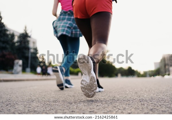 Back view of friends legs\
in sportswear running in the city. Multiethnic women having a\
fitness workout.