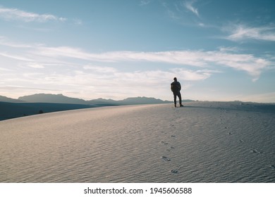 Back View Of Full Body Faceless Male Traveler Standing On Sandy Dune Against Blue Sky In White Sands National Park