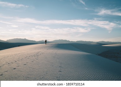 Back View Of Full Length Unrecognizable Male Traveler Walking On Empty Sandy Dune Against Cloudy Blue Sky In White Sands National Park