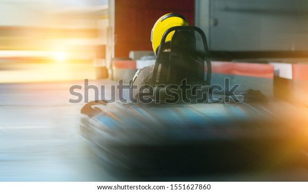 Back view\
of girl in helmet driving kart on a track\
