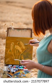 Back view of a girl painter depicting wheat spikelets on canvas. Young girl doing her favourite hobby - Shutterstock ID 2157077897