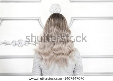 Back view of girl with pretty blond ombre hairstyle standing in hair salon, Balayage technique concept