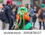 Back view of girl with red hair in hat with decorations, symbols of St. Patrick