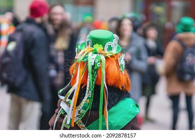 Back view of girl with red hair in hat with decorations, symbols of St. Patrick's Day, parade in city - Powered by Shutterstock