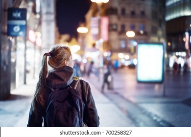 Back view of girl walking on city street at night, Prague