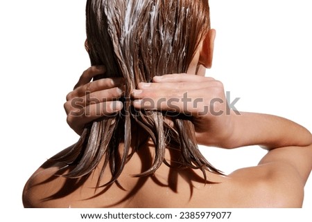 Back view of girl with wet hair, applying hair mask against white studio background. Conditioner treatment, nutrition. Concept of beauty, hair care, treatment, natural cosmetics. Copy space for ad