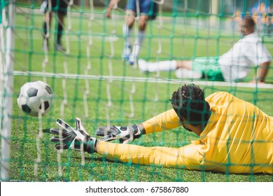 Back View Of Goalkeeper Catching Ball During Soccer Match On Pitch