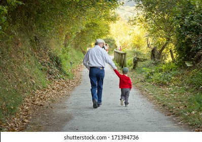 Back view of grandfather and grandchild walking in a nature path - Powered by Shutterstock