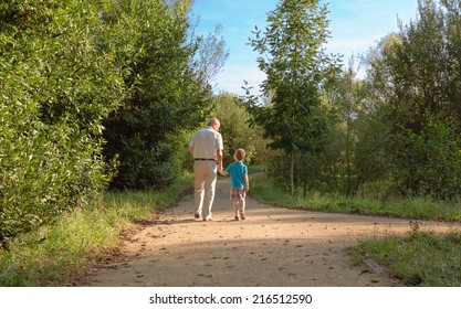 Back View Of Grandfather And Grandchild Walking On A Nature Path