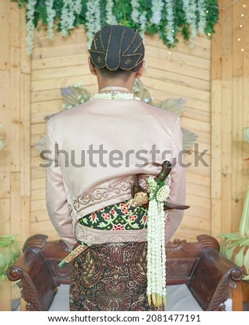 The back view of the groom wearing a dagger on the back.                               