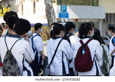 Back View Of Group Of Boy And Girl High Or Middle- School Students In White Uniform With Face Mask And Bags In Hong Kong