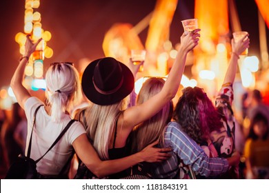 Back view of group of female friends at music festival drinking beer and dancing - Powered by Shutterstock