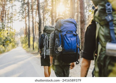 Back view group of friends with backpacks having travel trip in forest. Active lifestyle, going on track in woods together. Escaping the urban lifestyle, living wild life