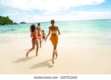 Back view of group of friends running to the tropical sea, having fun. Family vacation. Real people lifestyle. Summer vibes, Tropical island. - Powered by Shutterstock