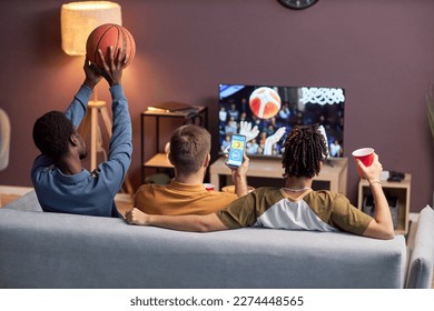 Back view at group of friends watching basketball match at home and drinking beer - Powered by Shutterstock