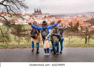 Back View Of Group Of People Hugging In Prague Park At Spring. Travel With Friends Concept