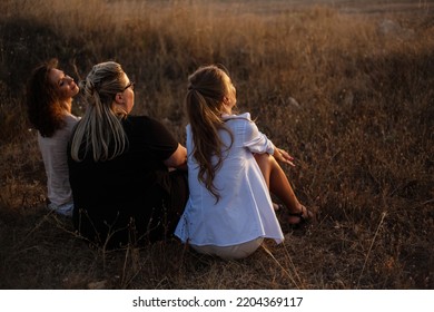 Back View Of Group Pf Three Friends, Plus Sizewith Two Thin Girls Spend Happy Time Together In The Nature. Overweight And Strong Women Have Fun, Enjoy The Momet Of Sunset .