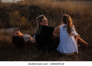 Back View Of Group Pf Three Friends, Plus Sizewith Two Thin Girls Spend Happy Time Together In The Nature. Overweight And Strong Women Have Fun, Enjoy The Momet Of Sunset .